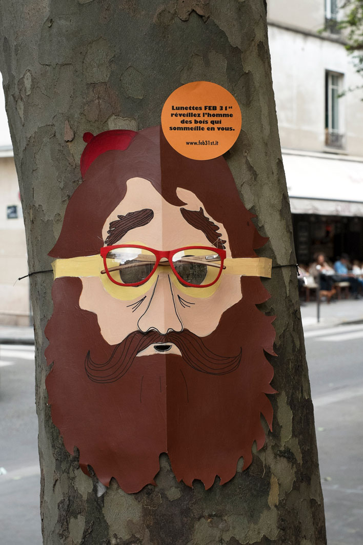 Street marketing, un masque de bucheron à lunettes rouges vives FEB 31 th est attaché sur un tronc d'arbre. Design les soeurs siamoises.