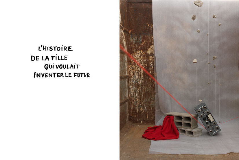 Cascade de cailloux attachés par des fils reliés à un amplificateur posé sur des parpaings dont sort un tissu rouge évoquant une mare de sang. 