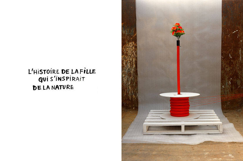 Tube de plastique de chantier orné d'un bouquet de fleurs rouge le tout relié par des fils. 