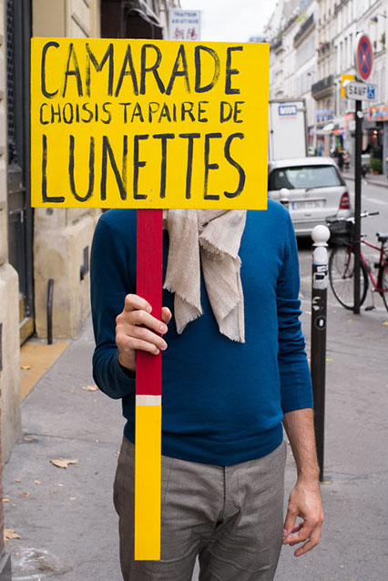 panneau de manifestant sur lequel est écrit camarade choisis ta paire de lunette fait main par les soeurs siamoises
