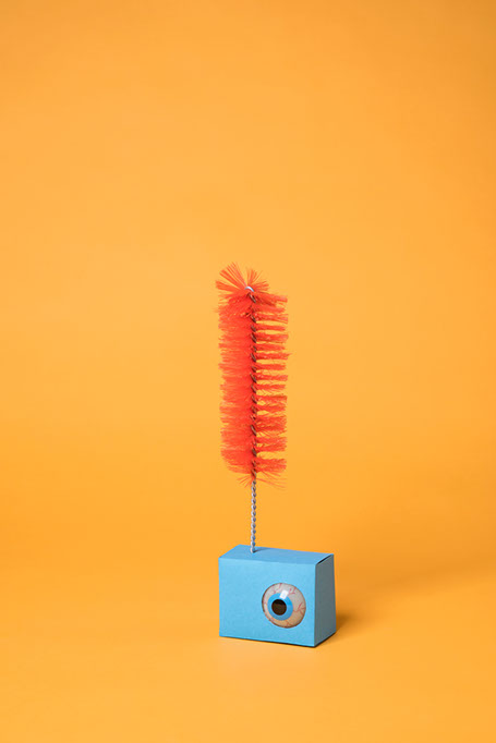 oeil enfermé dans une boite crise avec un plumeau au dessus enfoncé dans la boite design les soeurs siamoises