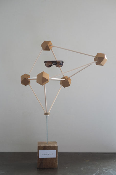 Présentoir en forme de molécule géante en carton et en balsa sur laquelle est suspendue une paire de lunette en carton par les soeurs siamoises